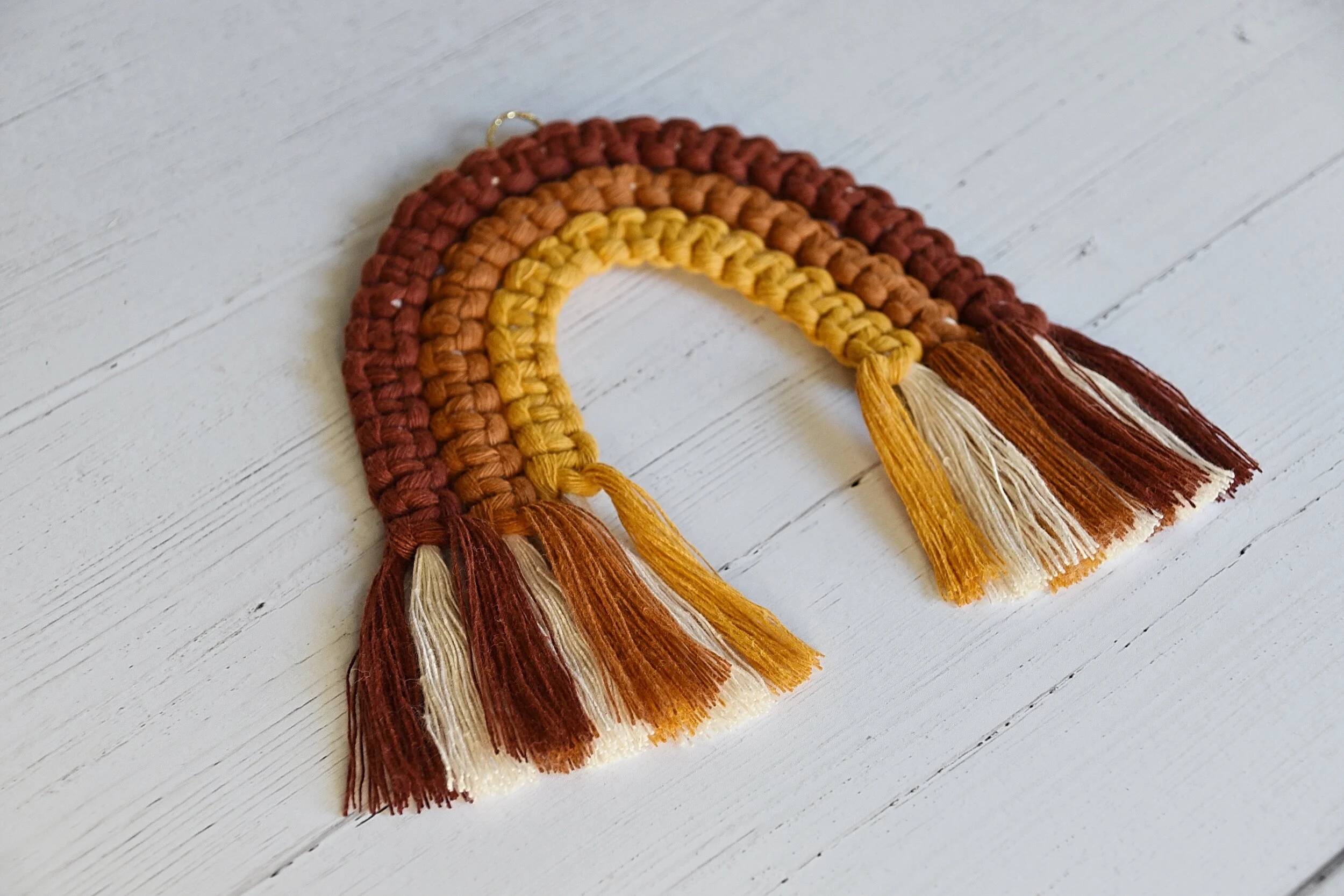 A colourful macram&eacute; rainbow wall decoration